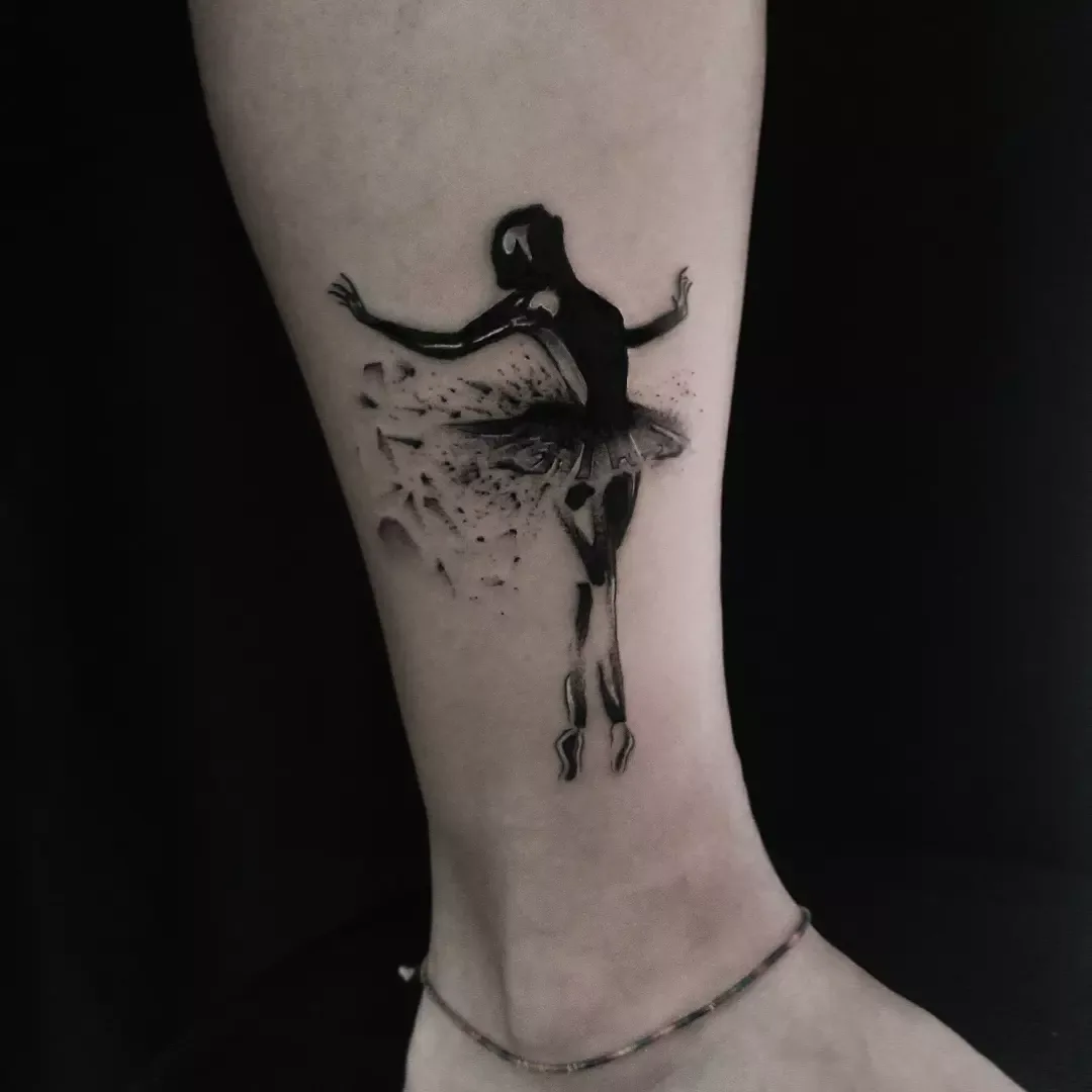 Eteği dağılan parçacıklara dönüşen bir balerini gösteren blackwork ayak bileği dövmesi